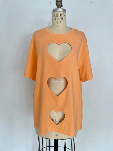 Peach t-shirt with three heart cut-outs displayed on a mannequin against a white background