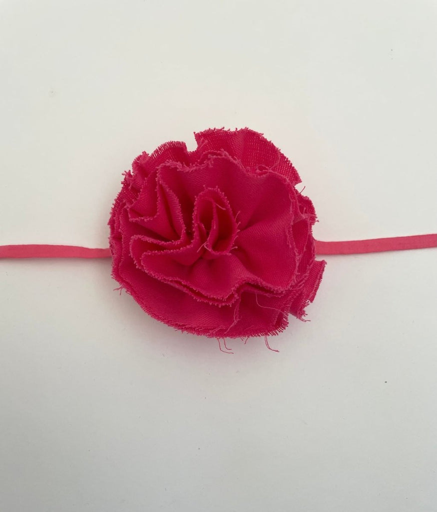 Pink fluffy flower accessory with frayed edges and elastic ties, displayed against a white background