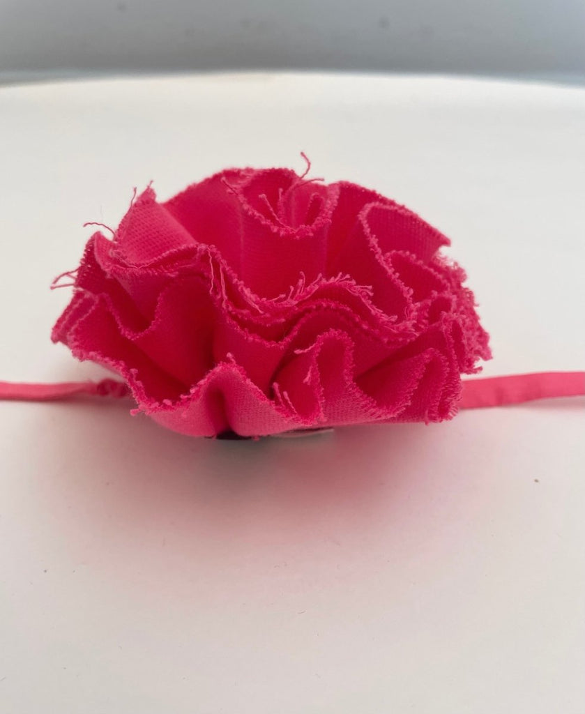 Pink fluffy flower accessory with frayed edges and elastic ties, displayed against a white background