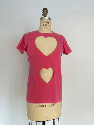 A pink fitted double heart cut-out T-shirt on a mannequin, showcasing the front view with a visible heart-shaped cut-out on the chest  and belly area.