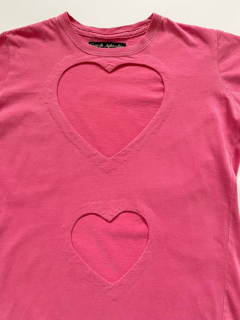 a close up of two heart cut outs on a pink repurposed T-shirt displayed flat on a white background