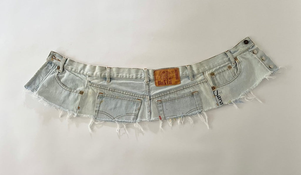Denim belt with frayed edges and a visible brand label on a white background