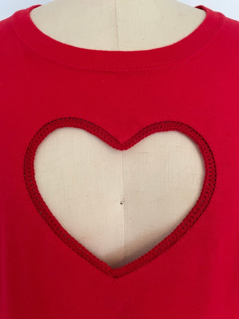 Red oversized crochet heart cut out T-shirt on a mannequin torso, showcasing a heart-shaped design with a crochet pattern around the edge.