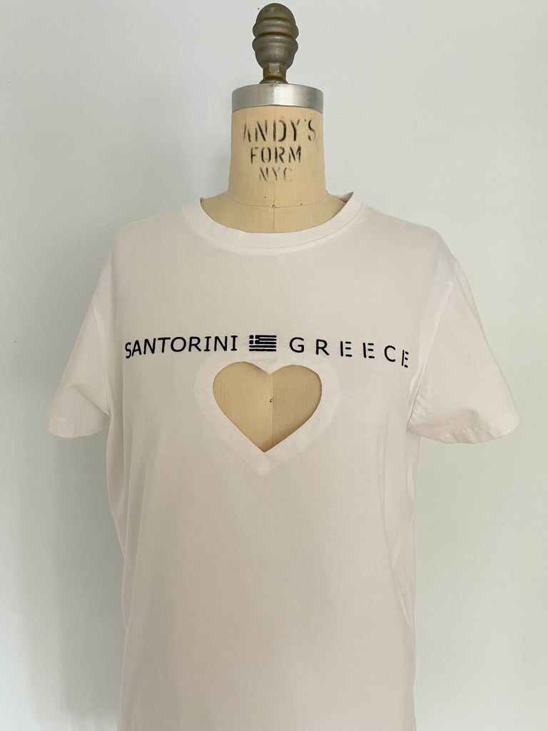 A white t-shirt with 'SANTORINI GREECE' text and a heart cut-out on the front, displayed on a mannequin.