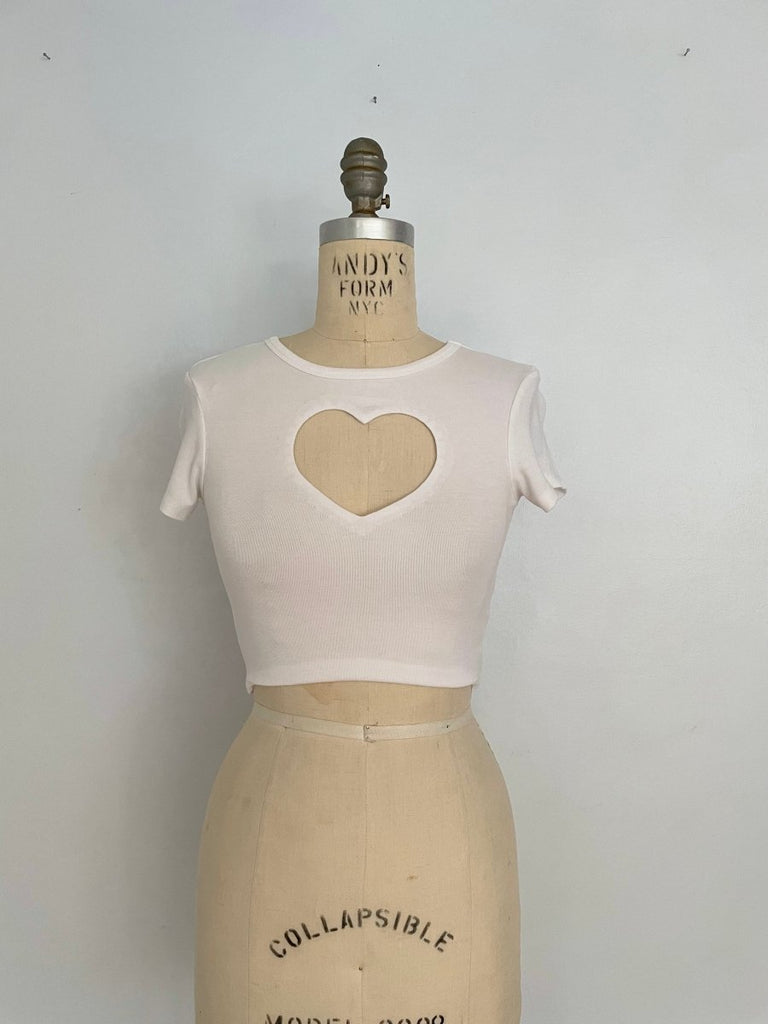 A white cropped t-shirt with a heart cut-out T-shirt on a mannequin torso, displaying a repurposed design 