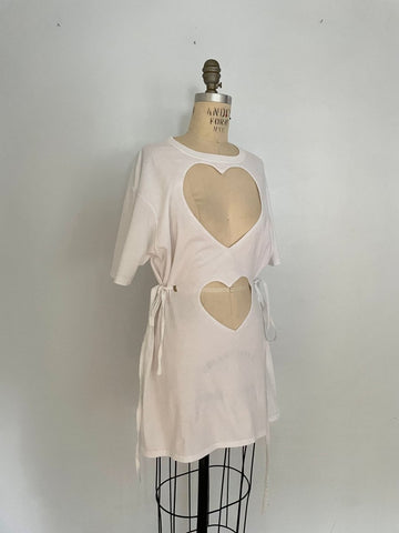 A white cotton t-shirt with double heart cut-outs and ties, displayed on a mannequin.
