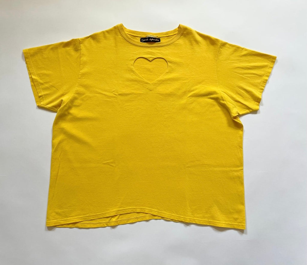 One-of-a-kind yellow heart cut-out tee made from a salvaged T-shirt by Sarah Aphrodite, layed out flat on floor