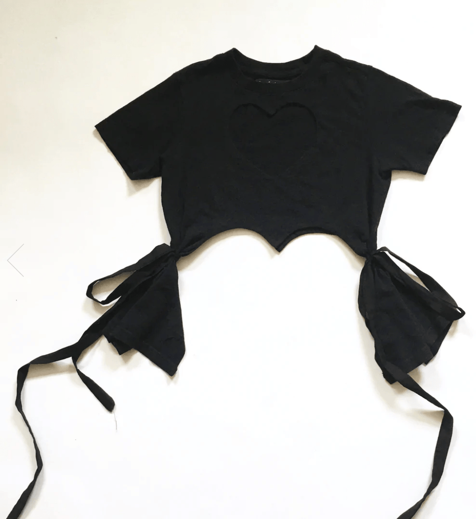 Fitted black heart cut-out T-shirt with tassels by Sarah Aphrodite, handmade from repurposed cotton. Playful, sensual, and one-of-a-kind sustainable fashion. photographed flat against a white background