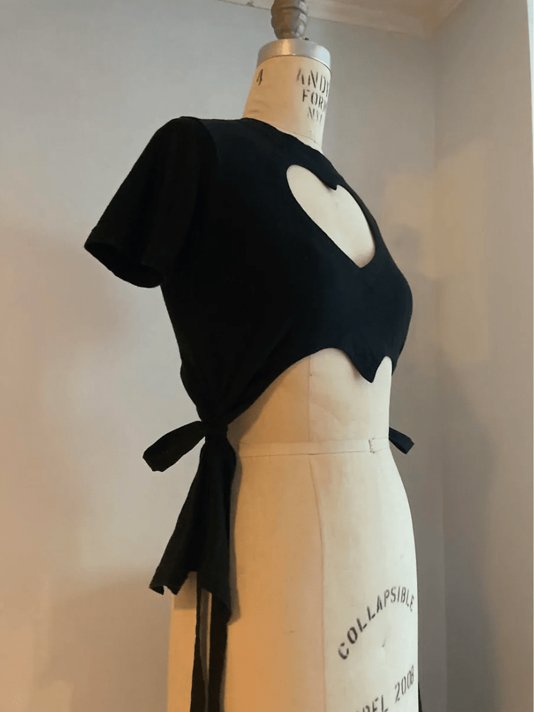 Fitted black heart cut-out T-shirt with tassels by Sarah Aphrodite, handmade from repurposed cotton. Playful, sensual, and one-of-a-kind sustainable fashion.