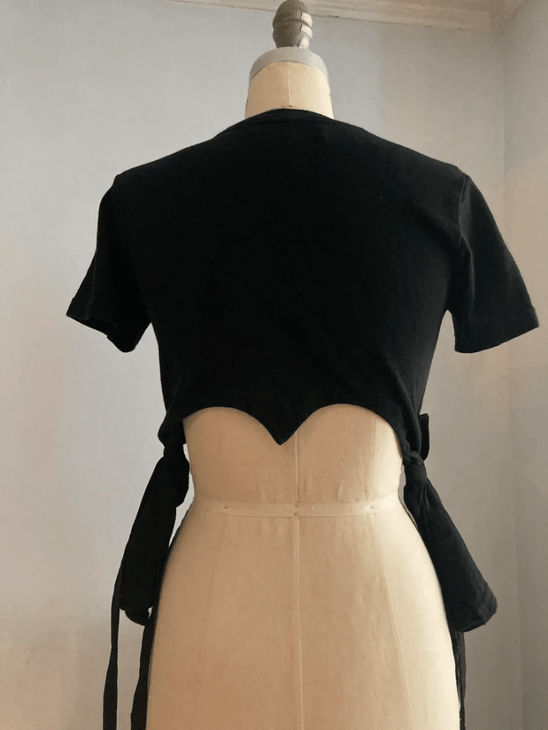 Fitted black heart cut-out T-shirt with tassels by Sarah Aphrodite, handmade from repurposed cotton. Playful, sensual, and one-of-a-kind sustainable fashion.