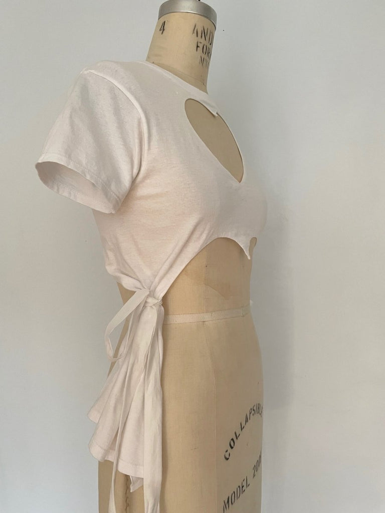 Fitted white heart cut-out T-shirt with tassels by Sarah Aphrodite, handmade from repurposed cotton. Playful, sensual, and one-of-a-kind sustainable fashion.