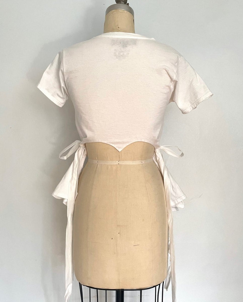 Fitted white heart cut-out T-shirt with tassels by Sarah Aphrodite, handmade from repurposed cotton. Playful, sensual, and one-of-a-kind sustainable fashion.