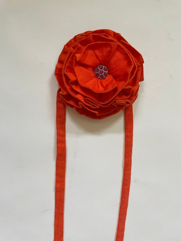 Handmade one-of-a-kind orange flower hair clip by Sarah Aphrodite, featuring a purple button gem center, silver clip, and long ties made from upcycled SA scrap fabrics.