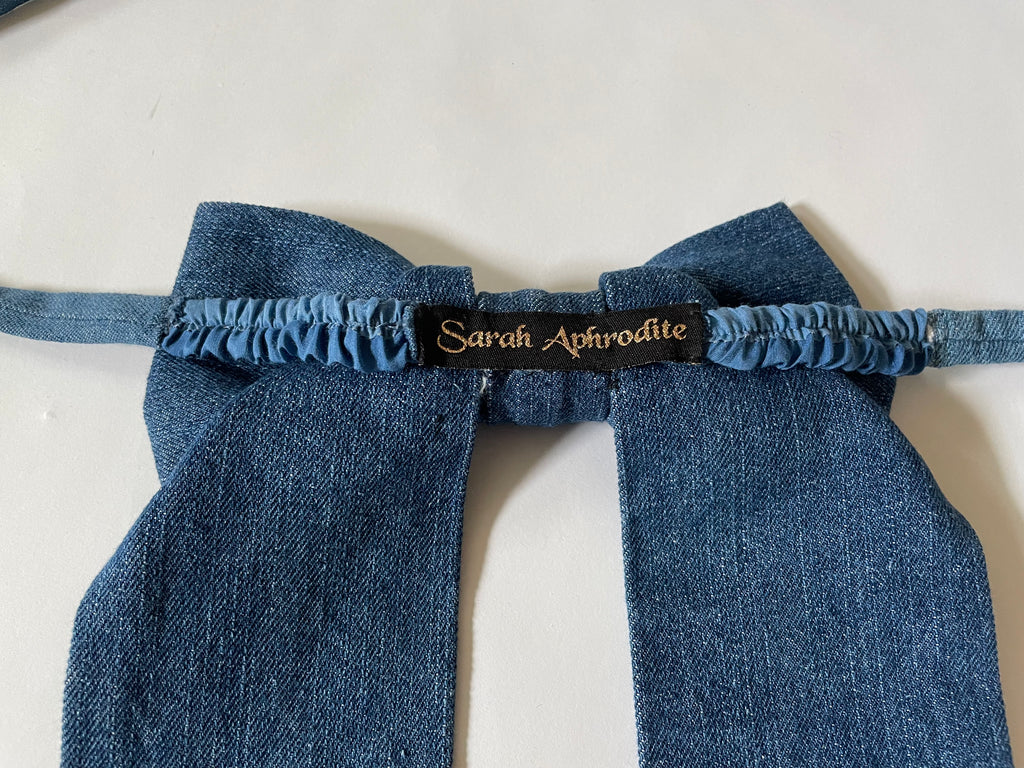 Handmade one-of-a-kind dark blue denim bow garter by Sarah Aphrodite, made from repurposed denim scraps, with long ties for versatile styling on arm, thigh, or waist.
