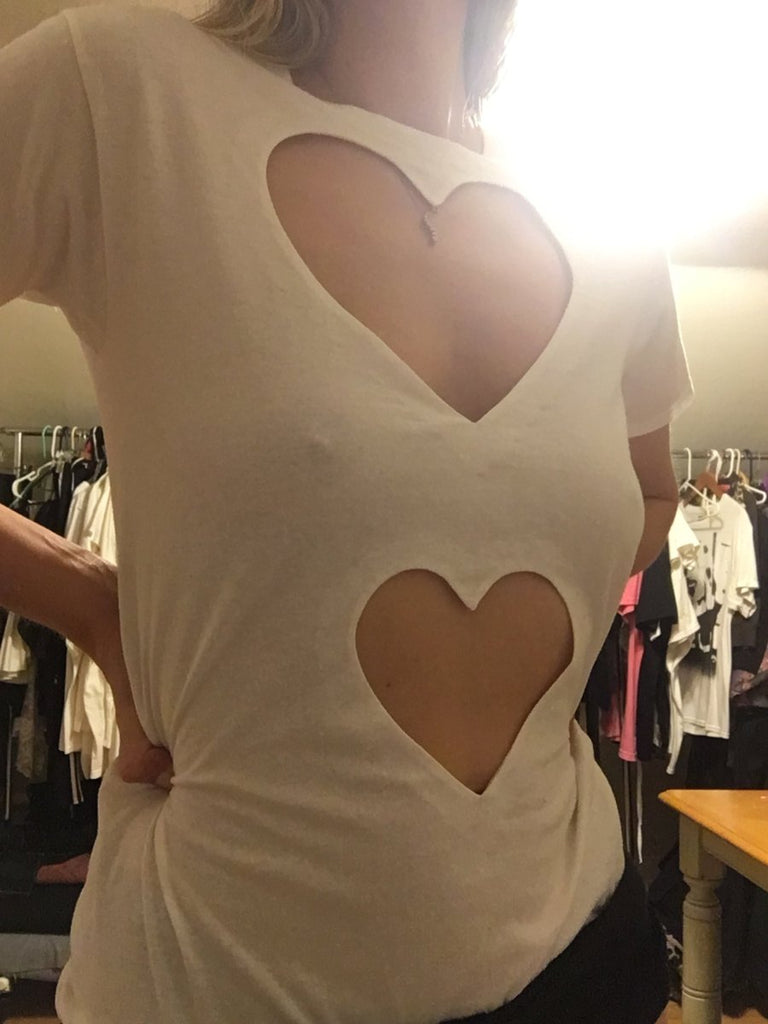 Fitted double heart cut-out t-shirt by Sarah Aphrodite, handmade from repurposed black or white cotton. Features two hand-cut heart openings, unique markings, and a fitted silhouette for layering or wearing solo.