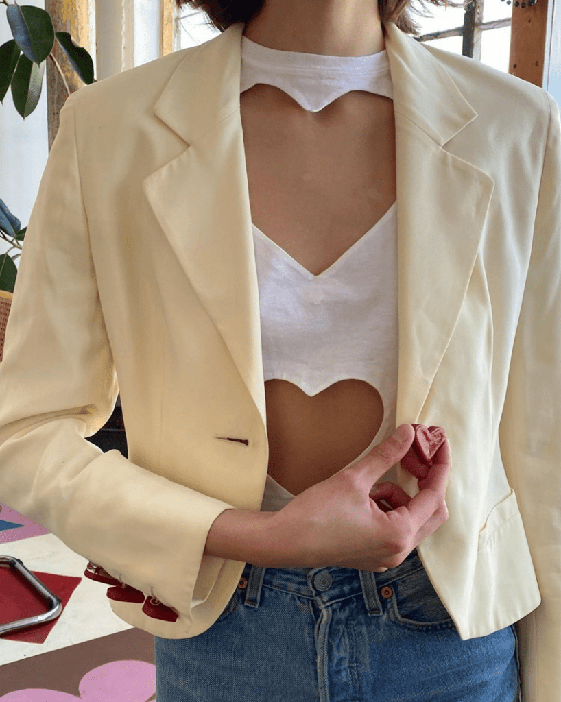 Fitted double heart cut-out t-shirt by Sarah Aphrodite, handmade from repurposed black or white cotton. Features two hand-cut heart openings, unique markings, and a fitted silhouette for layering or wearing solo.