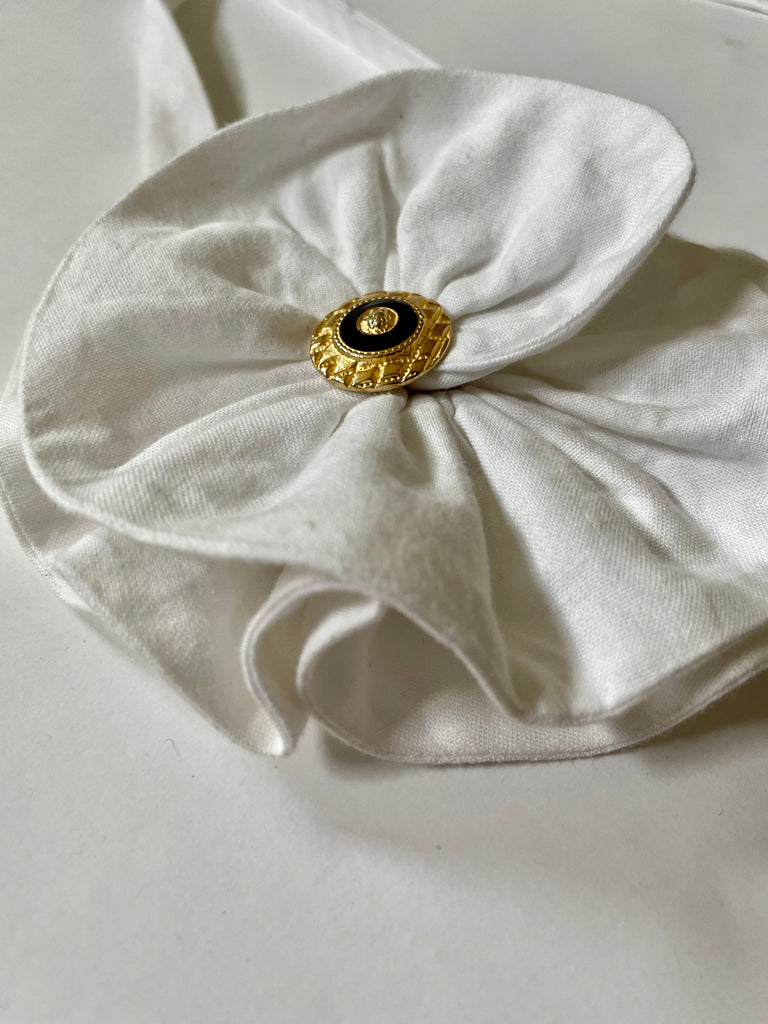 Handmade one-of-a-kind white flower accessory by Sarah Aphrodite, featuring a gold nautical button and made from upcycled SA scrap fabrics. Versatile wear as necklace, bracelet, anklet, upper arm, or garment embellishment.