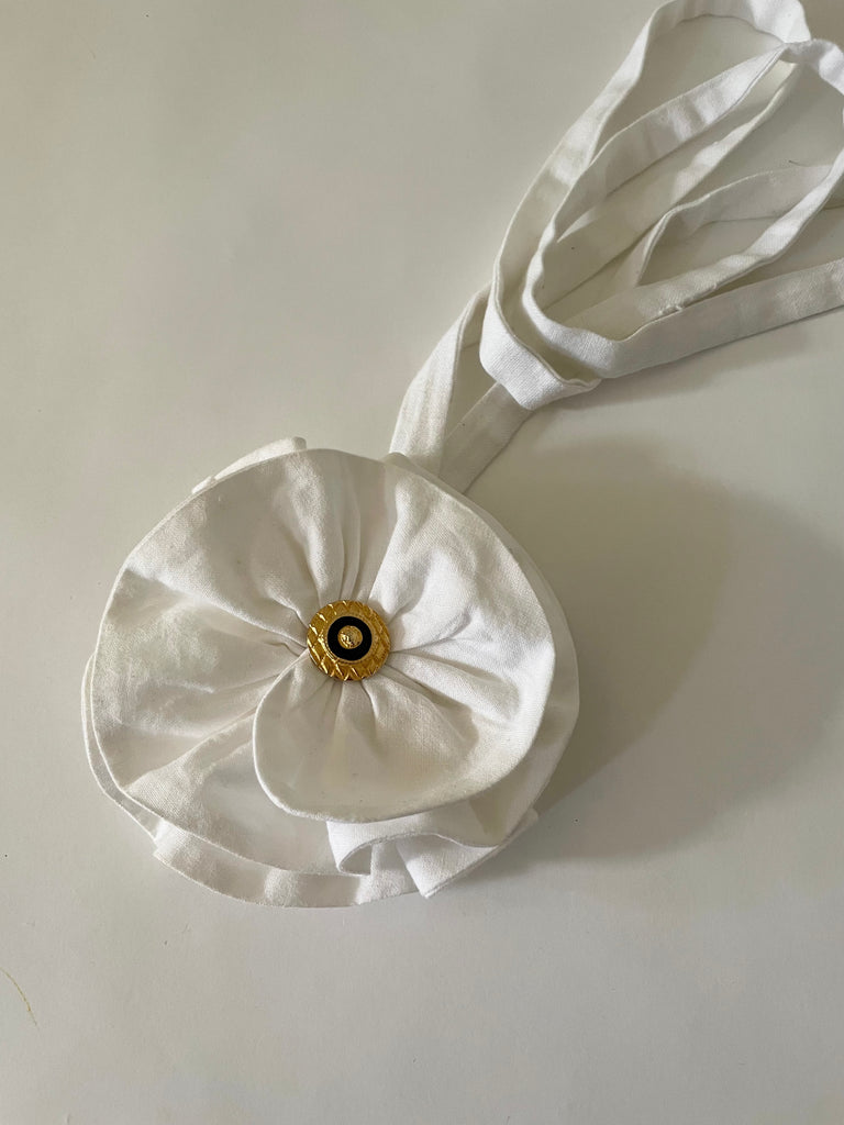 Handmade one-of-a-kind white flower accessory by Sarah Aphrodite, featuring a gold nautical button and made from upcycled SA scrap fabrics. Versatile wear as necklace, bracelet, anklet, upper arm, or garment embellishment.