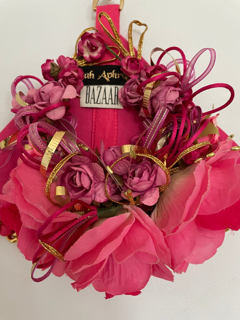 close up view of pink triangle-shaped archival bag with handmade Mexican flowers